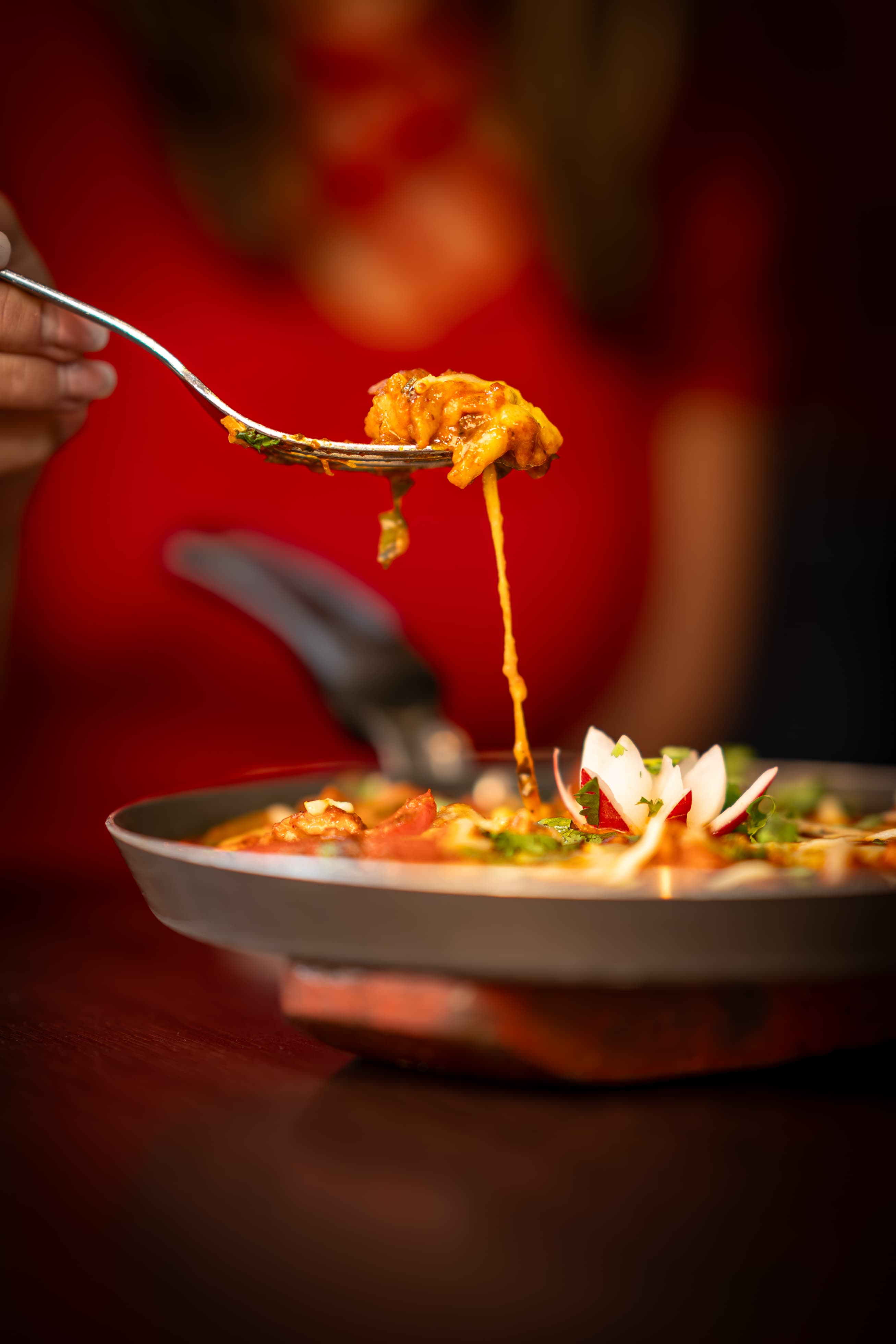 Fork lifting a bite of curry with melted cheese